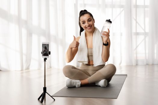 Female fitness coach recommending water drinking, broadcasting from home